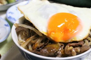 おばあがつくった「牛の炊いたん」をご飯に乗せた「牛丼」。そこに目玉焼きをトッピング