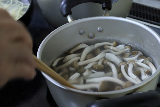 インスタントの富山ブラックラーメンをつくるために、しめじと豚肉が入った鍋の湯を温めているところ