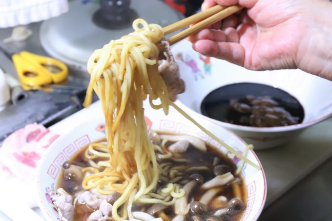インスタントの富山ブラックラーメンの麺を箸で持ち上げて混ぜているところ