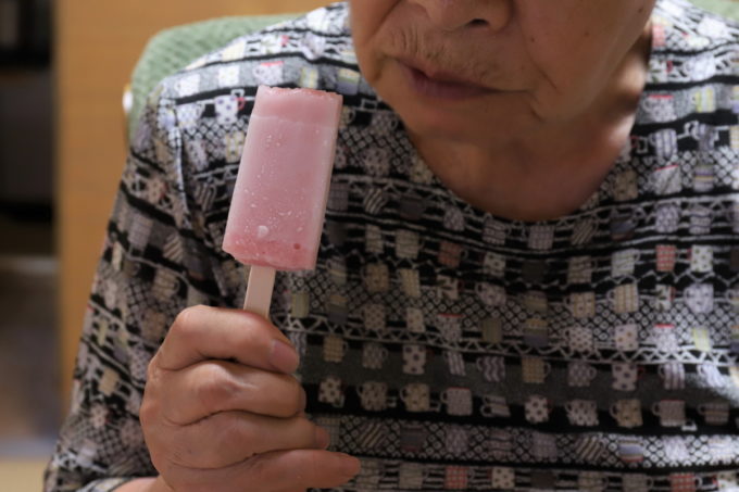 ブドウ味のアイスキャンディーを手に持つ祖母