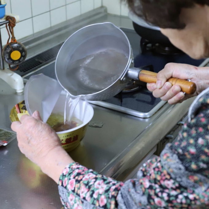 カップのマルちゃん正麺にお湯を注ぐ祖母（おばあ）