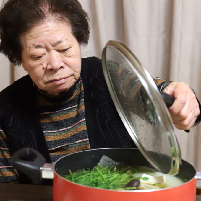 水炊きの鍋のフタを開けている祖母（おばあ）