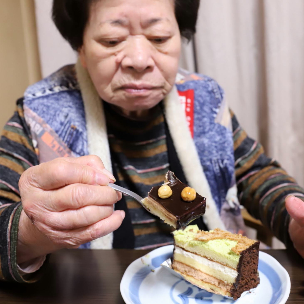 チョコレートケーキをスプーンですくって食べている祖母（おばあ）