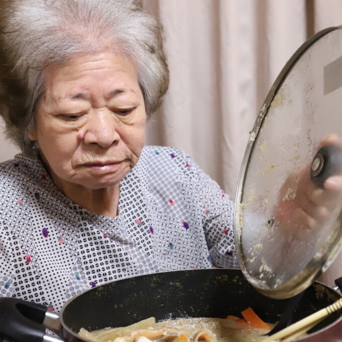 食卓に着いて鍋の蓋を開ける祖母・おばあ