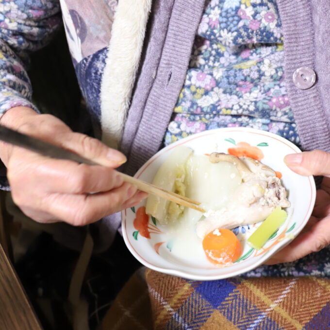 孫が作った豆乳鍋を食べる祖母