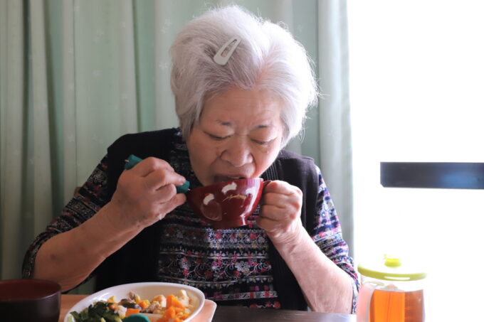 お椀を手に持ち、とうもろこしごはんを頬張る祖母