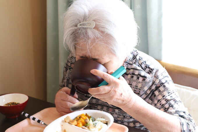 お椀に入ったコーンポタージュをすする高齢の祖母