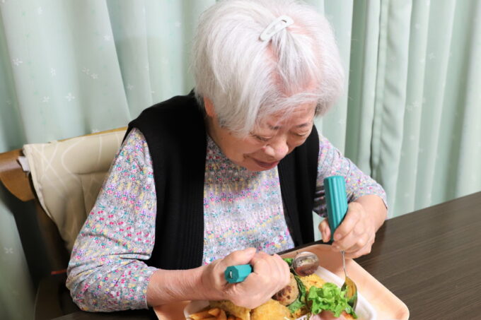 介護用スプーンを使って食事をする高齢の祖母