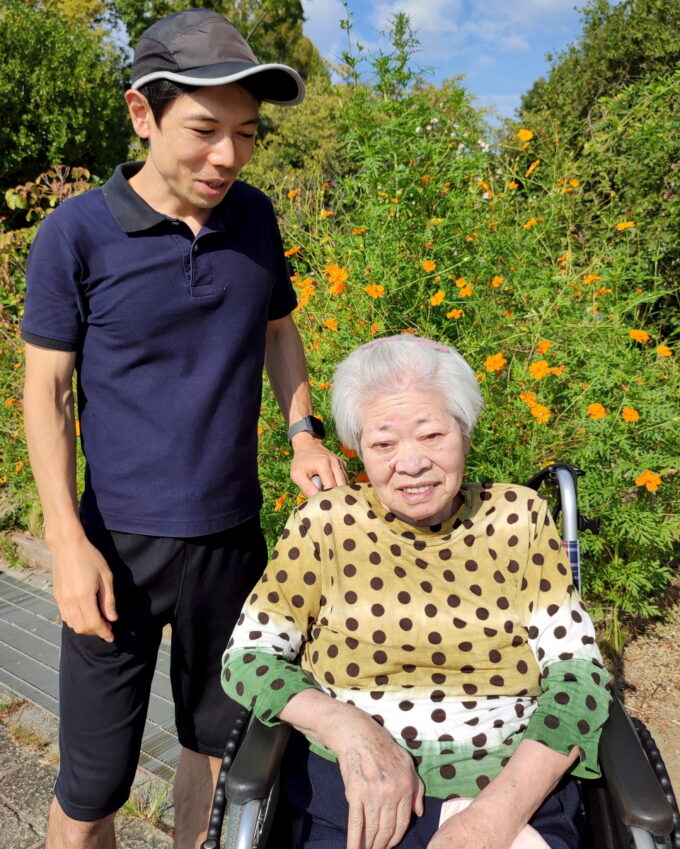 公園の花を背景にした車椅子に乗った祖母と孫
