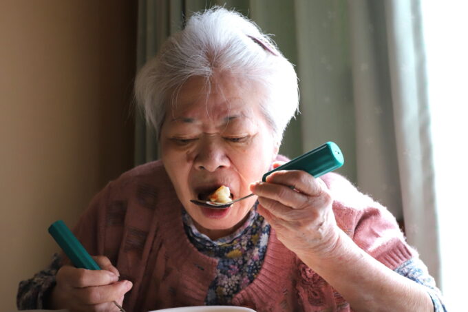 介護スプーンで餃子を食べる祖母
