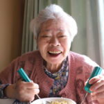 孫が作った料理を食べて笑顔の祖母（おばあ）