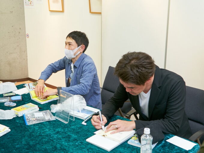 『おばあめし』出版記念イベントで書籍にサインする大迫知信と近藤雄生