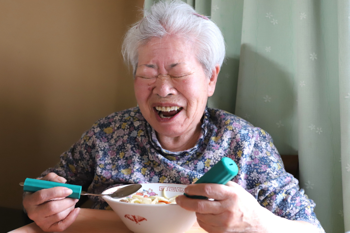 孫が作った料理を食べて笑顔の祖母（おばあ）