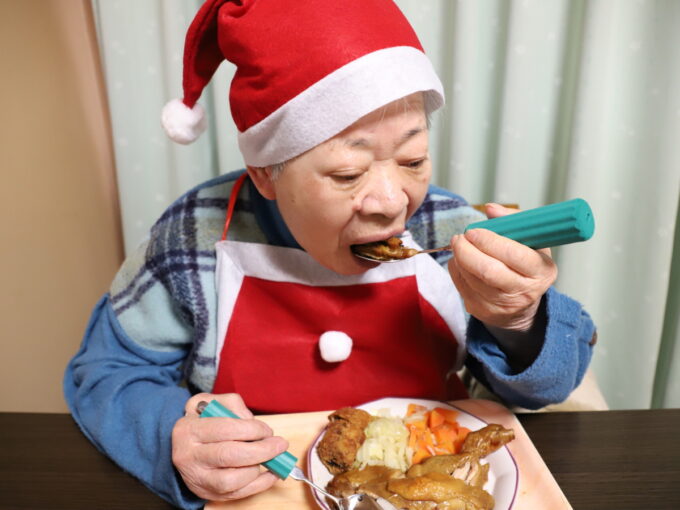 クリスマスのディナーを食べるサンタクロースの服装をした祖母