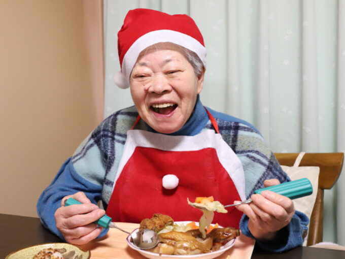 クリスマスのディナーをサンタクロースのコスチュームで食べる祖母（おばあ）
