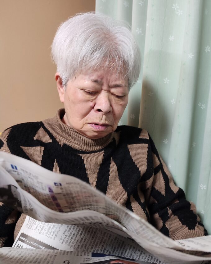 新聞を読んでいるしかめっ面の祖母