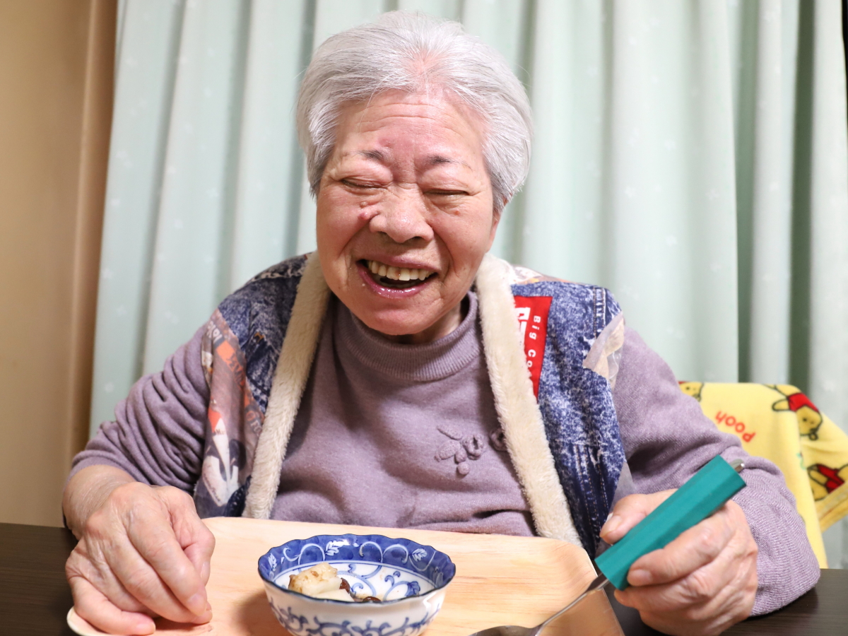 餅を食べて笑顔の祖母