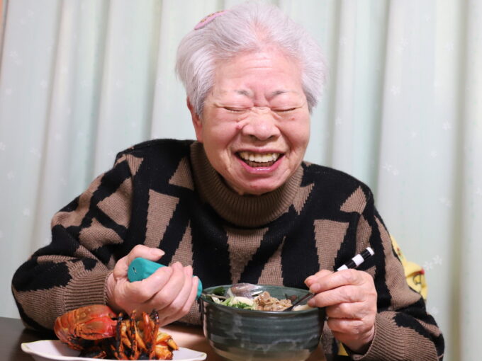 正月の料理を前にして笑顔の祖母（おばあ）