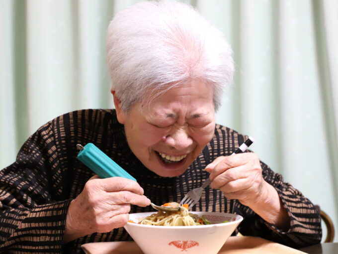 ラーメンを食べて笑顔の祖母