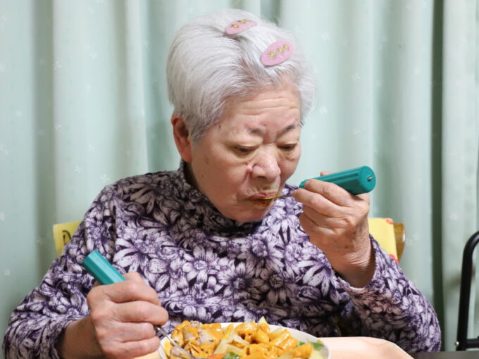 介護用スプーンで食事をしている祖母
