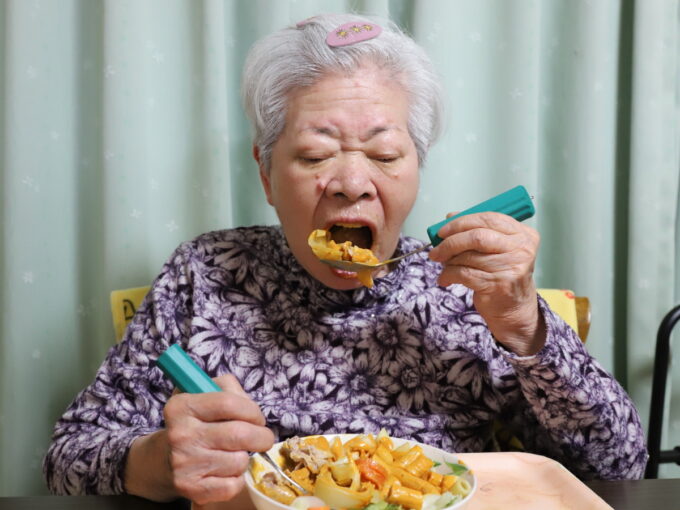 介護用スプーンを使い、大きな口を開けて食事をするおばあちゃん（おばあ）