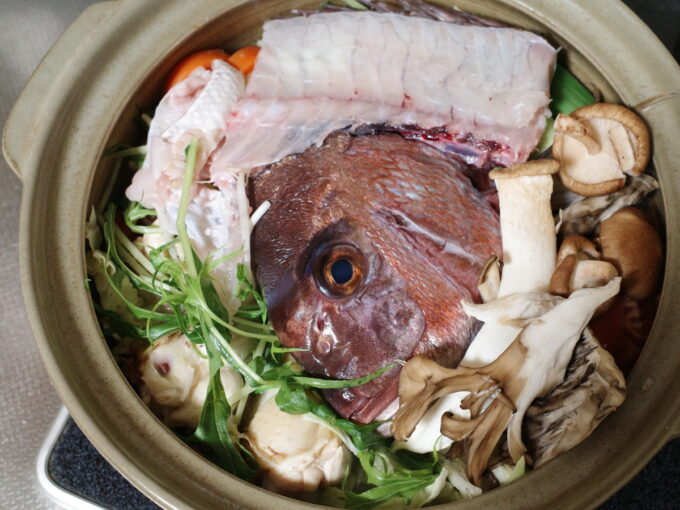鯛のアラやきのこ、野菜など、土鍋に入れて調理しているところ