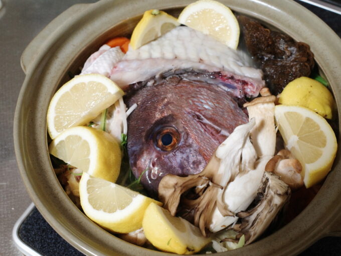 土鍋でアクアパッツァ風の鍋を作っている途中。鍋の具材は鯛のアラや野菜、レモンなど