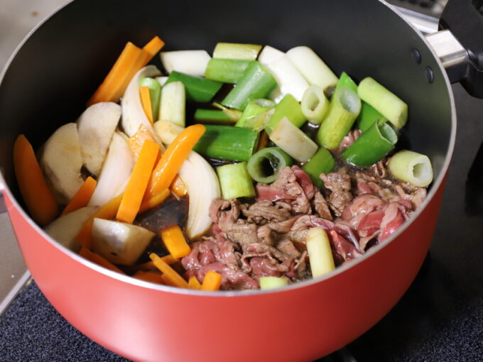 鍋に牛肉や野菜を入れてすき焼きを調理しているところ