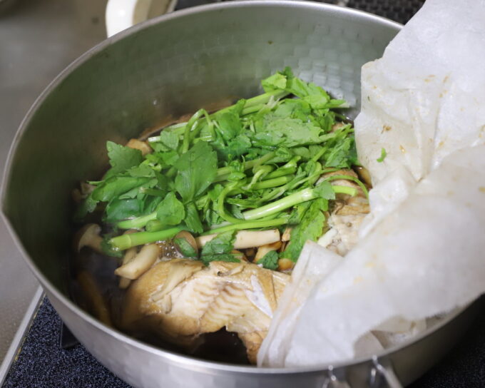 鍋にカレイの切り身とセリを入れて煮ている