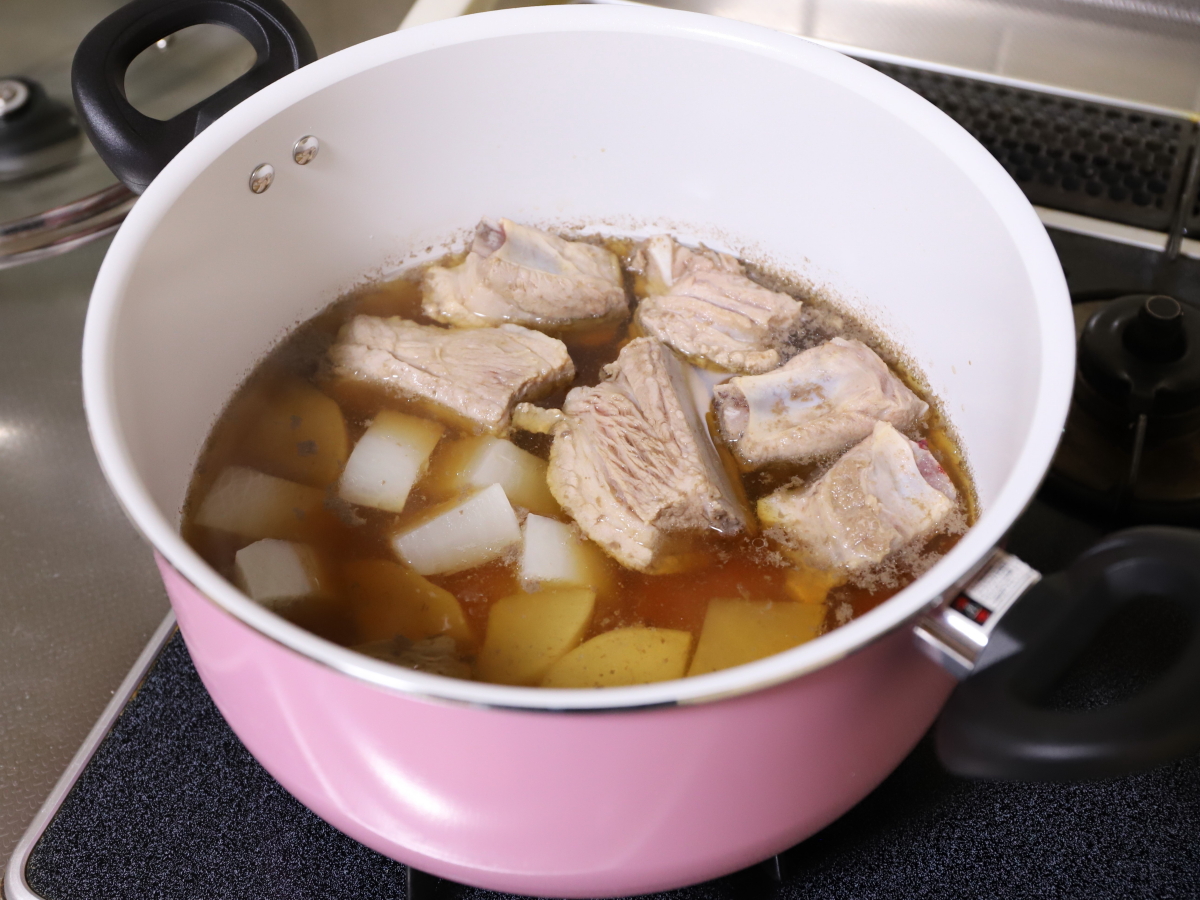 鍋に豚肉と大根を入れて煮込んでいる