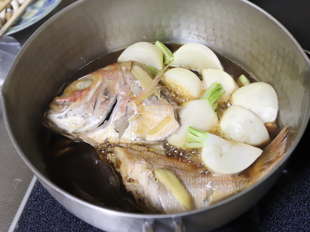 調味料の入った鍋に並べて調理しているカブと魚（鯛）