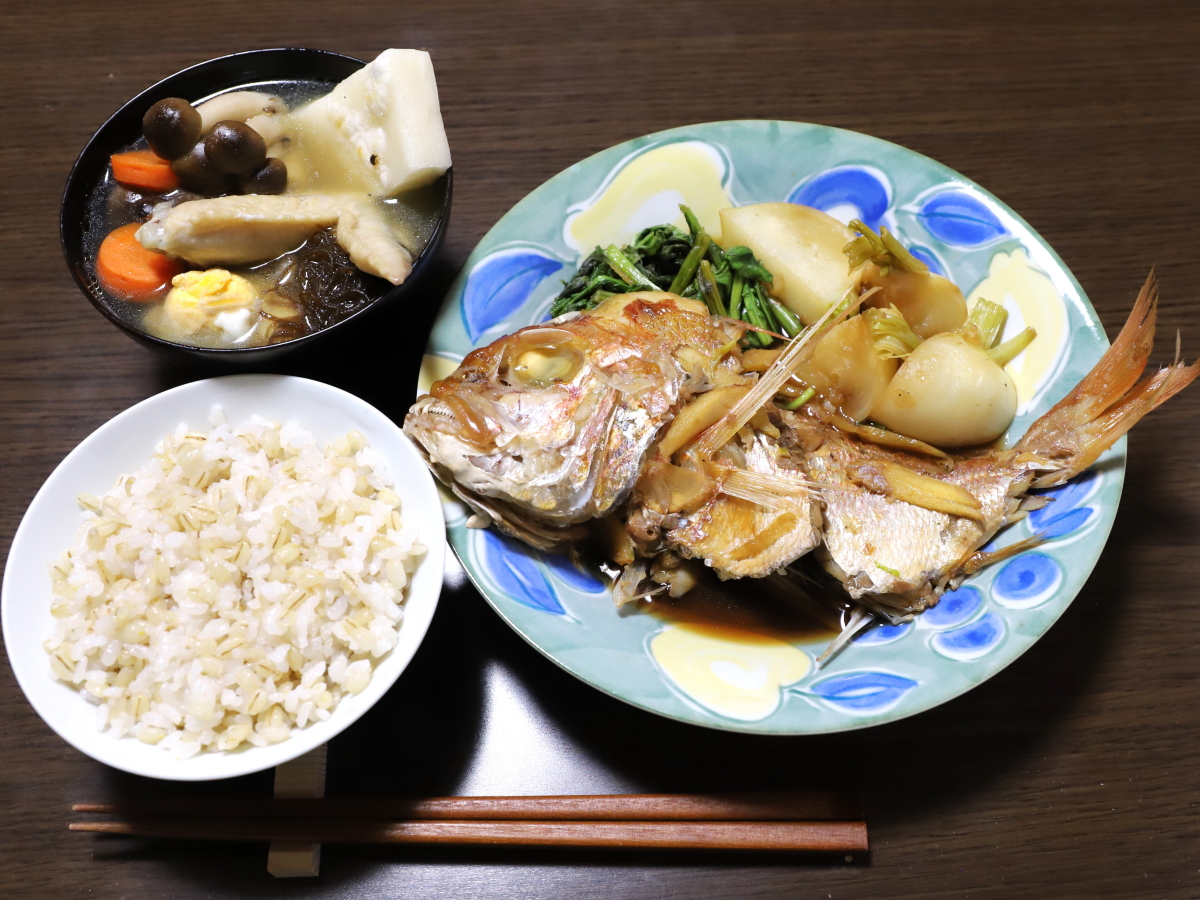 食卓に並べた晩ごはんの献立、ごはんをよそった茶碗、お椀に入れた雑煮、皿に盛りつけた魚（レンコ鯛）の煮付け