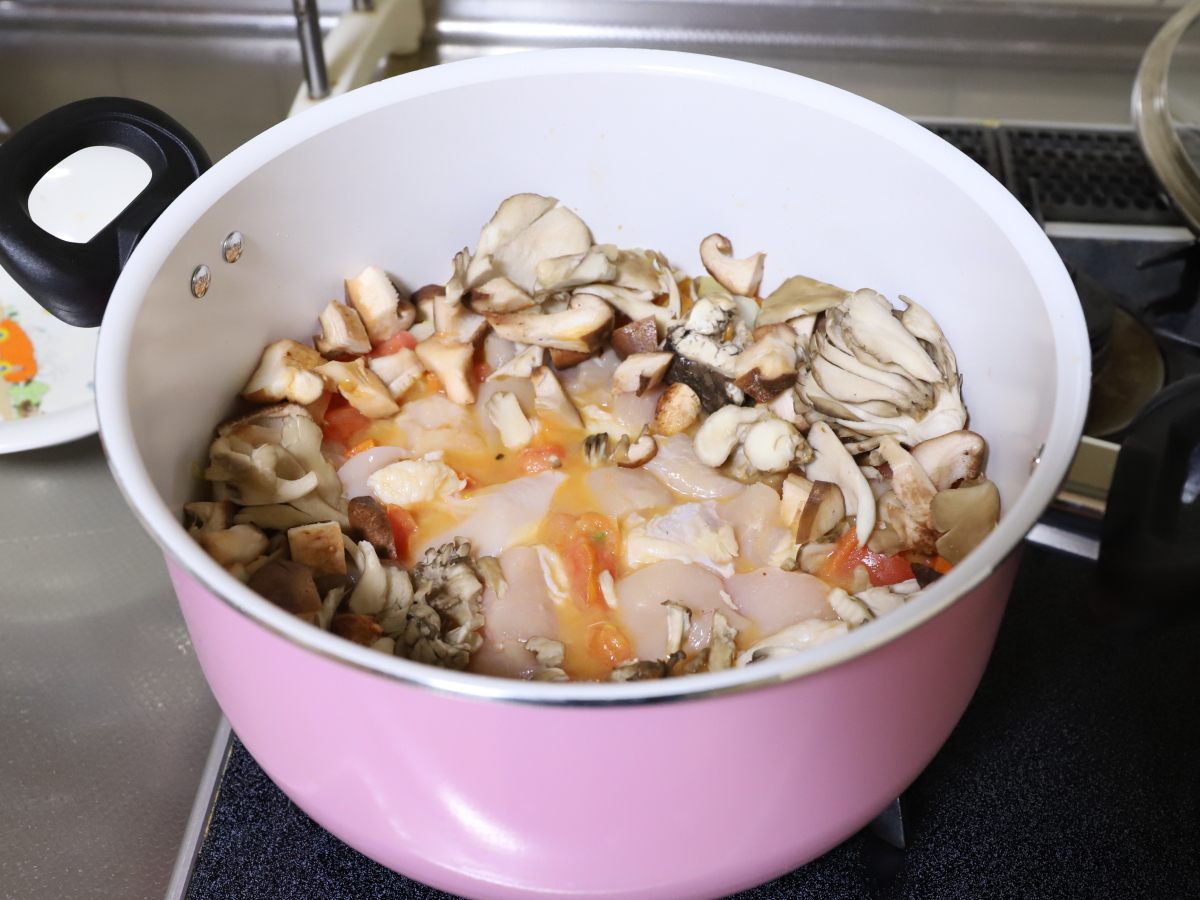 鍋で野菜やキノコ、鶏肉を煮てバターチキンカレーを作っているところ