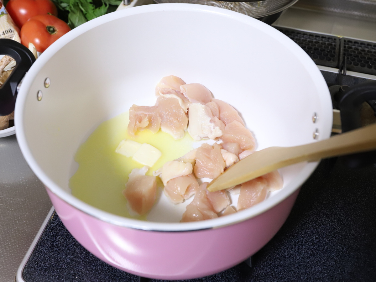 クリームシチューを作るために鍋でバターと鶏肉を炒めている