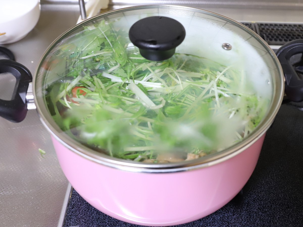食材を入れた鍋にフタをして煮込み、調理している