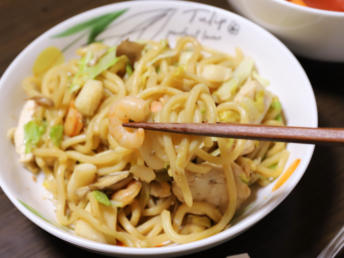 エビ入りの焼きそばを箸でつまんで食べようとしているところ