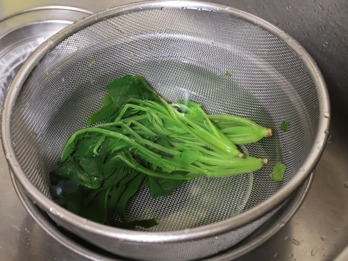 ボウルとザルに水をためて冷やしている茹でたホウレンソウ