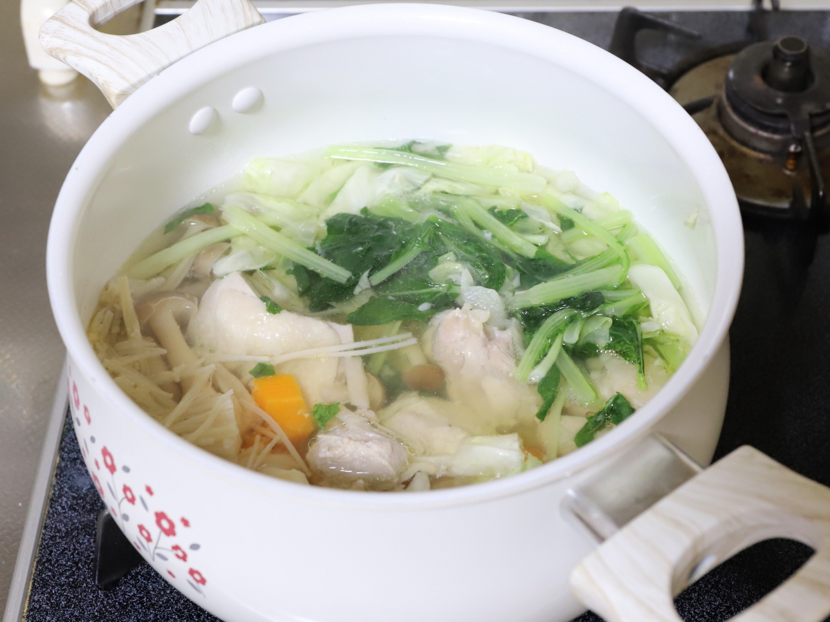 鍋に小松菜や鶏肉、にんじんなどを入れた塩麴スープを作っているところ