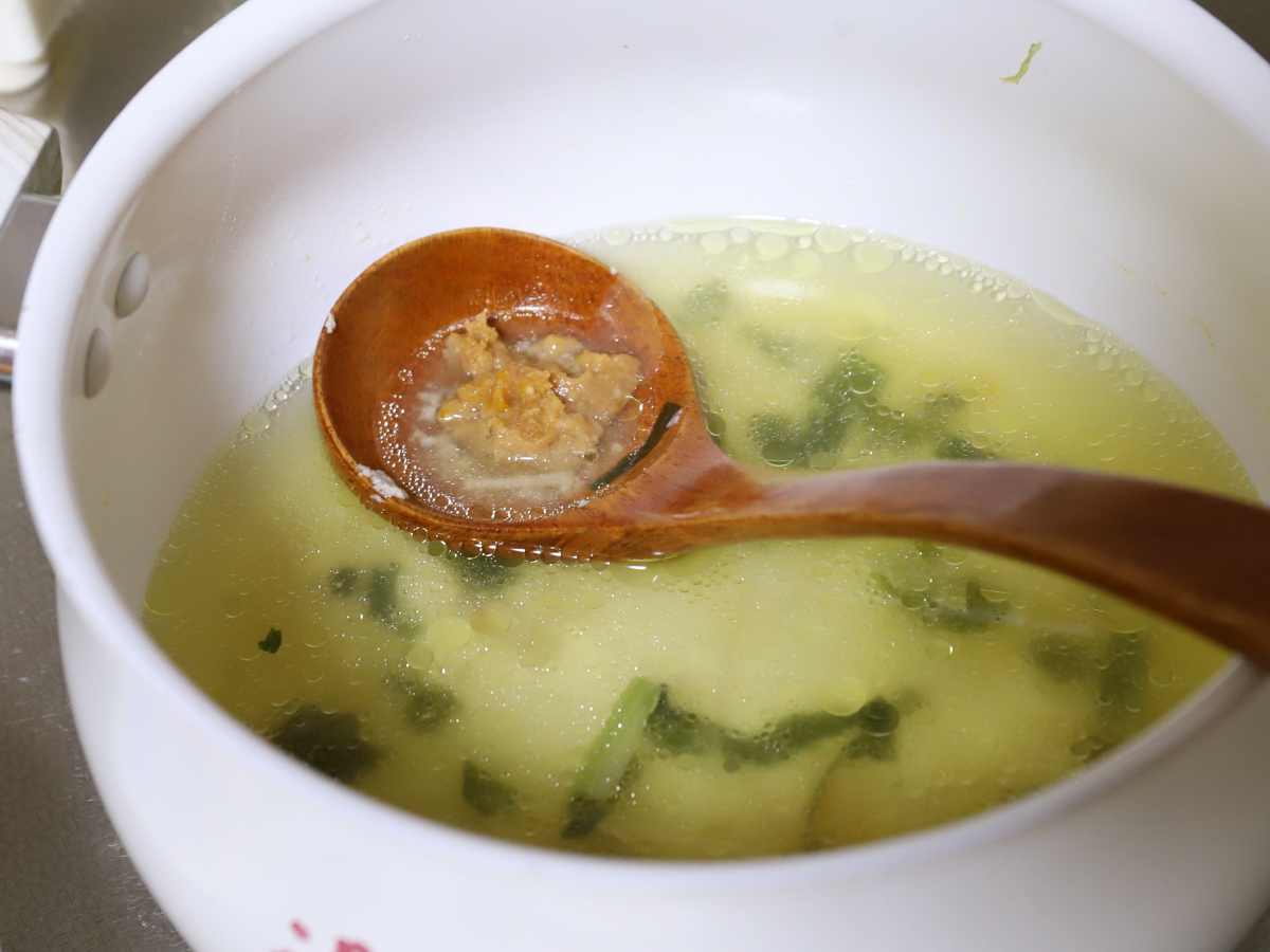 味噌をすくったお玉を塩麴スープに入れて、味噌汁を作っているところ
