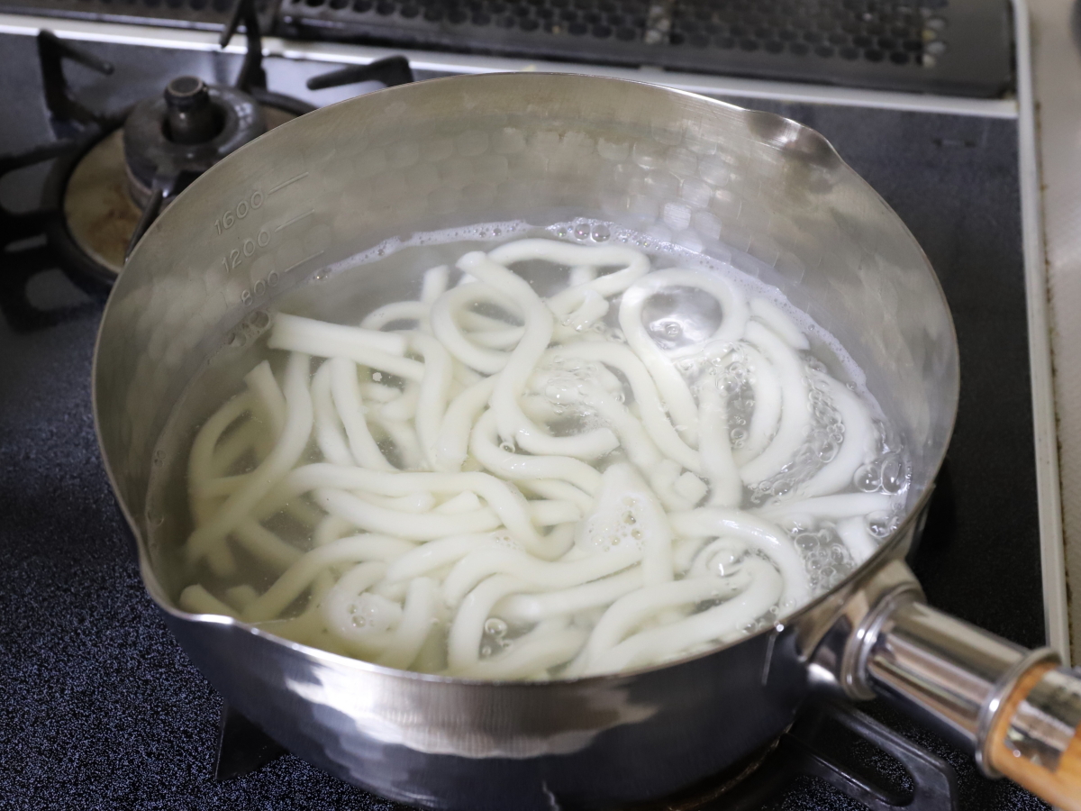 ステンレスの鍋で茹でているうどん