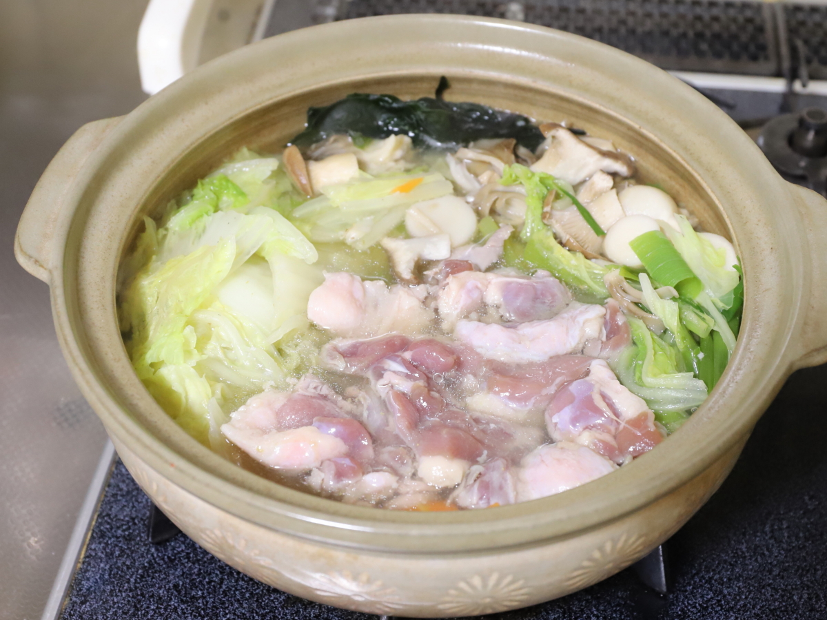 土鍋に野菜や鴨肉を入れて調理途中の鴨鍋