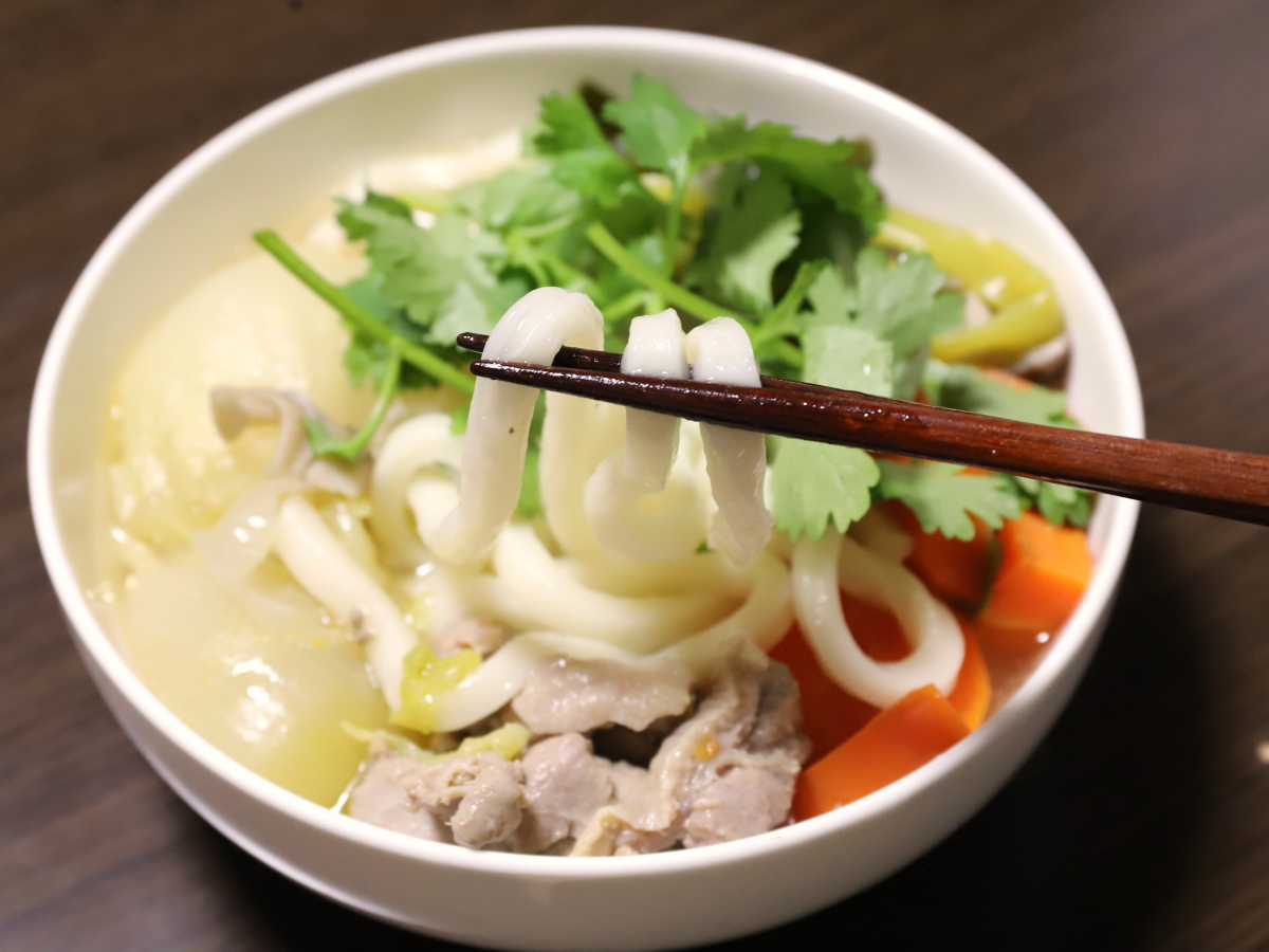 鍋のシメのうどんを箸でつまんでいる